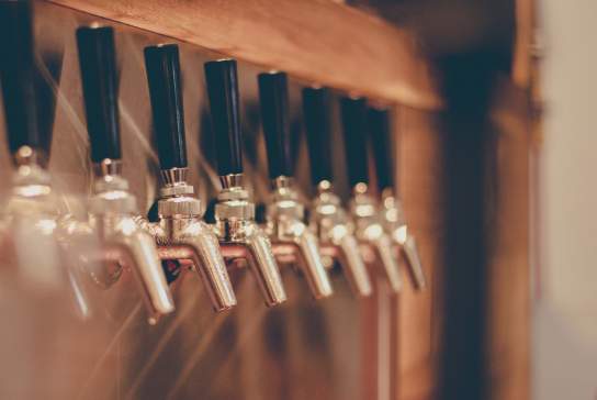 Photograph showing an array of taps mounted to a wall at a pub
