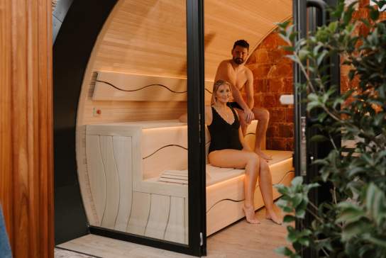 Couple sit in a sauna pod as part of a spa day experience
