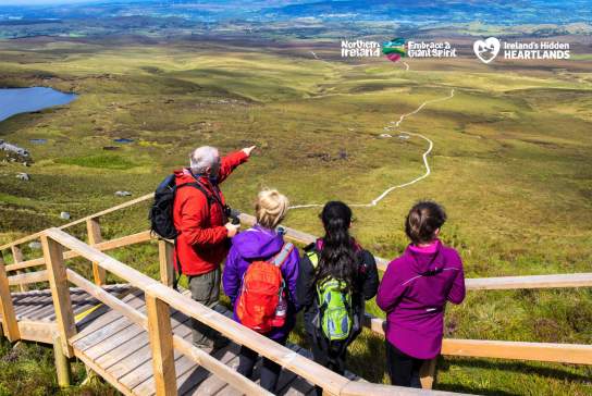 Group of walkers looking out over the landscape from the boardwalk at Cuilcagh Mountain.