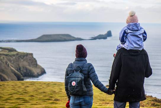 A man and a woman looking out at Worm's head. The man has a child on his shoulder.