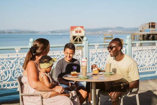 A family enjoying food outdoors on Mumbles Pier.