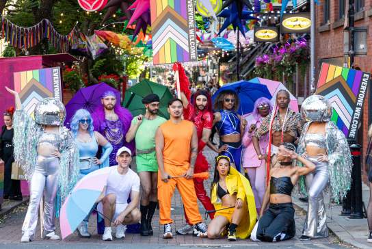 Group of people stood in colourful dress on canal street in Manchester