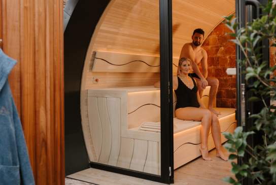 Couple sit in a sauna pod as part of a spa day experience