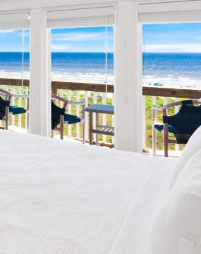 Beautiful condo bedroom with floor to ceiling windows looking out on the beach