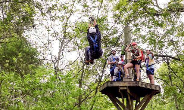 Young man ziplining through trees
