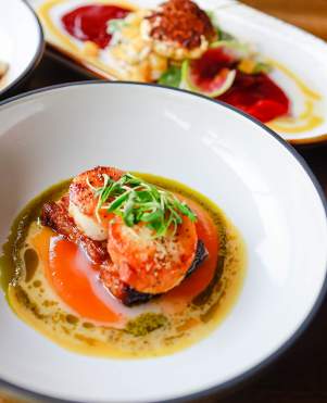 Three plates full of delicious foods like shrimp and steak