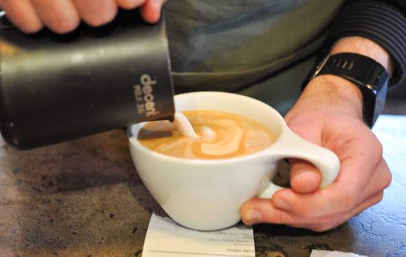 pouring milk into a coffee cup