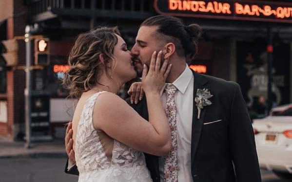 Couple stands in front of Dinosaur BBQ after getting married