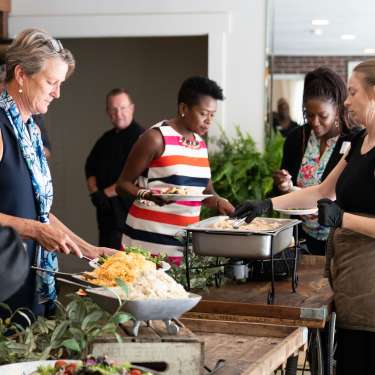 a woman serves food at a buffet line