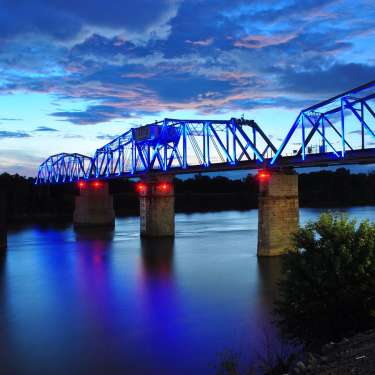 lighted train bridge over a river at sunset