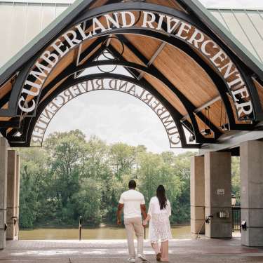 couple walking to a river under a large pavilion
