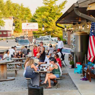 people at tables outside of a brewery