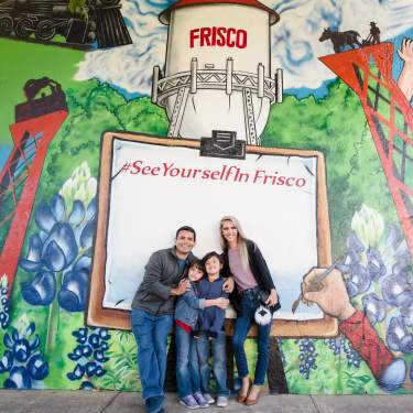 Family of four posing infront of the mural in the Rail District