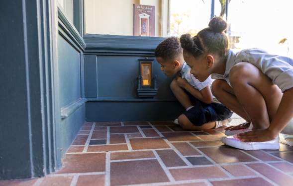Two children kneeling down to look in a fairy door