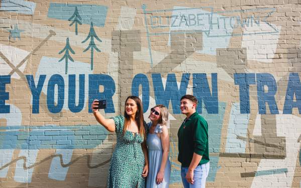 Three friends posing in front of a mural located in Downtown Elizabethtown, KY