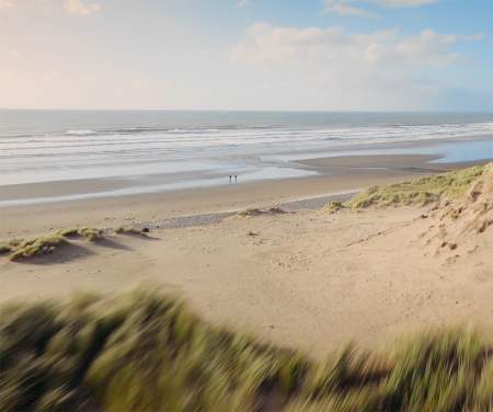 Two figures walking on a deserted beach