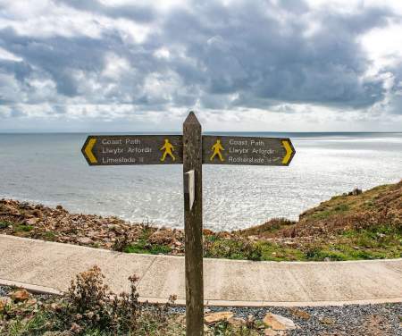 Coast path sign with the sea in the background.