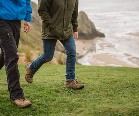 Legs of two walkers near the coast.