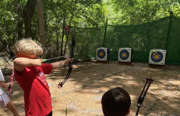 Two boys doing archery at camp.