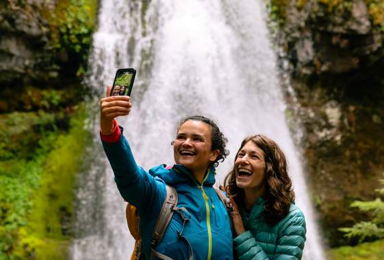 A couple takes a selfie in front of a waterfall