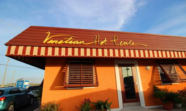 Red and orange building with a sign that says "Venetian Hot Plate."