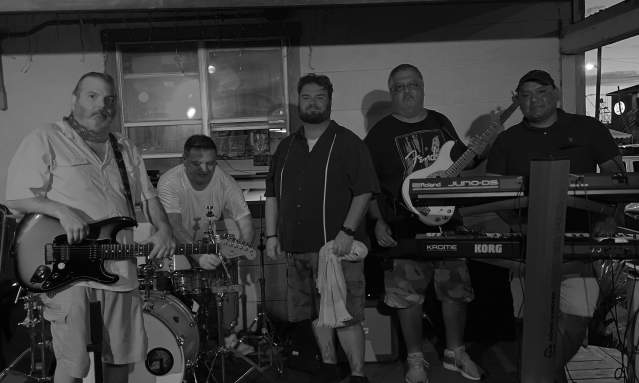 Black and white photo of five men sitting or standing at instruments.