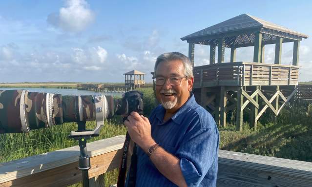 Headshot of a bearded man with a giant camera standing at the Leonabelle Turnbull Birding Center
