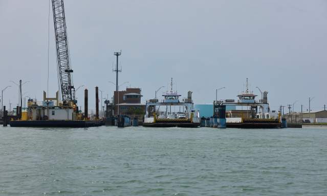 Across the water, cars are loaded on two ferry boats