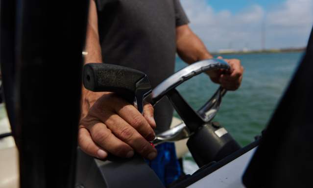 A close up of two weathered hands driving a boat