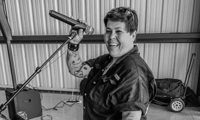 Black and white photo of a woman smiling while holding on to a microphone