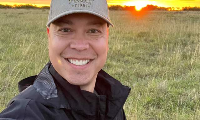 headshot in front of a large field with a sunset behind