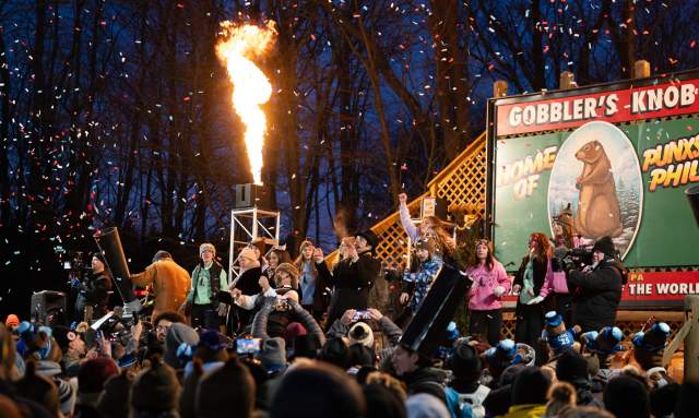 Huge crowd looking up at a stage that reads Gobblers Knob with people cheering and a blast of fire is coming out of a section of the stage