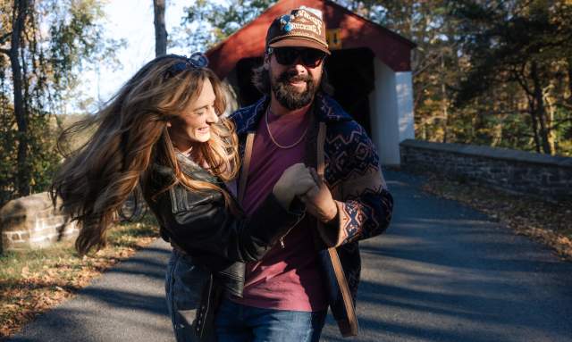 A man and woman hugging while walking on a paved road of a covered bridge