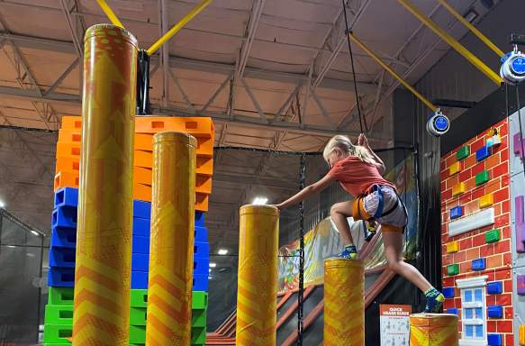 A girl climbing an obstacle course at Urban Air