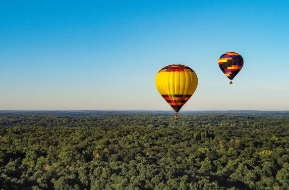 Two hot air balloons floating over Bloomington's rolling hills