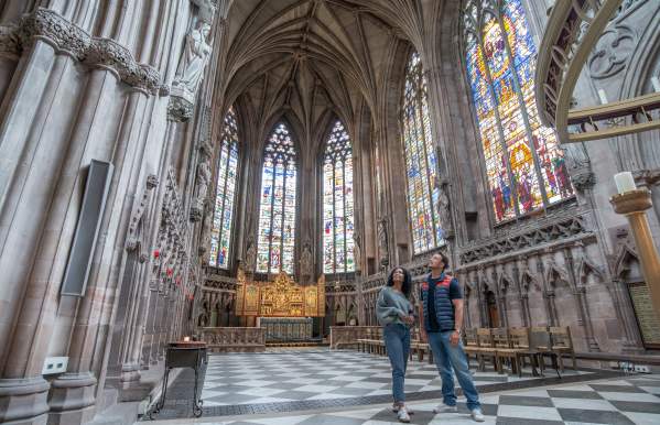 man and woman inside Lichfield Cathedral admiring the Herkenrode stained glass windows.