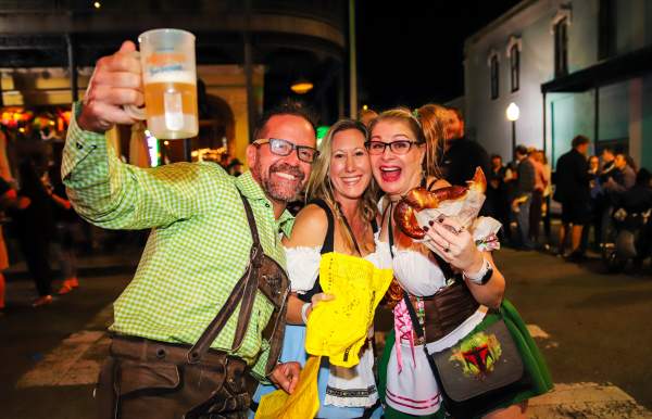 Two women and a man holding a beer bug and a pretzel