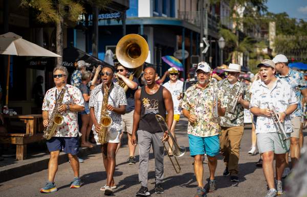 A group of musicians walking down Dauphin Street in downtown Mobile.