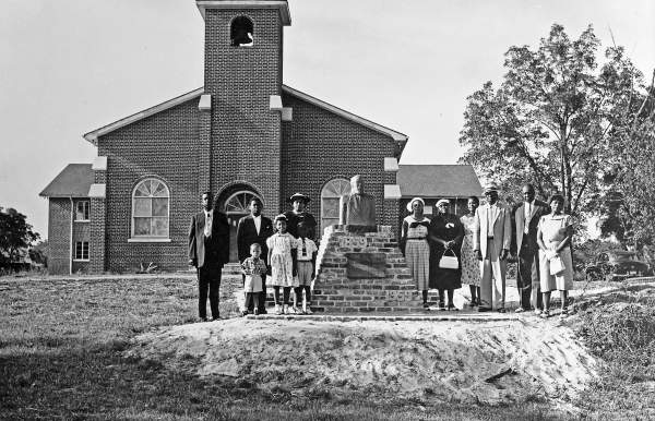 black and white photo of a group of people standing in front of a church