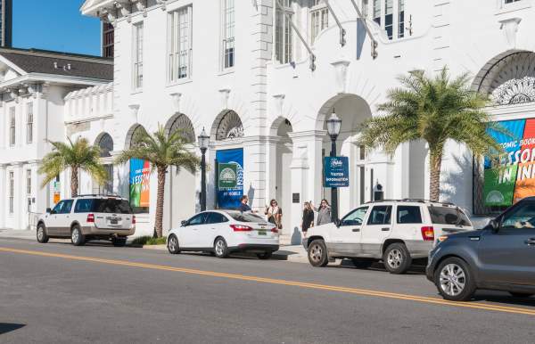 vehicles parked on the side of the road in front of a historic building