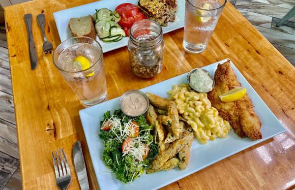 two plates of food on a table - fish, mac and cheese, fries, greens