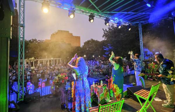 Women on stage clap as an audience cheers them on