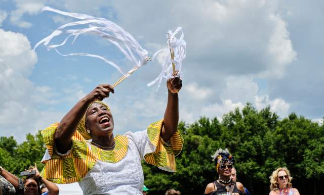 African American woman in traditional dress waving ribbons in the sky