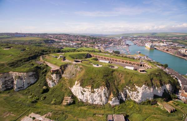 Aerial view of the grounds and red brick buildings of Newhaven Fort with sea in the distance