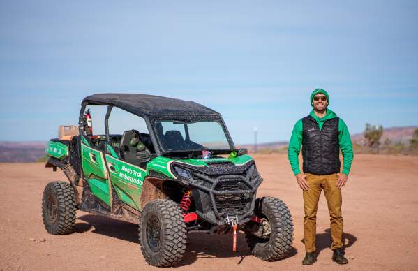 A Moab Trail Ambassador stands next to an OHV