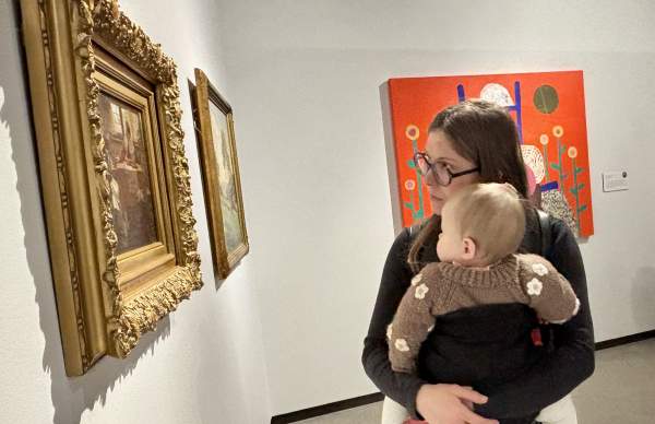 Woman holding baby looks at painting at Muskegon Museum of Art