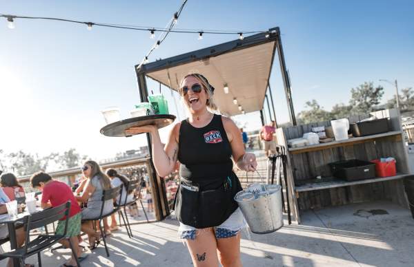 laughing waitress carries tray of drinks and bucket of iced beer at the deck restaurant in muskegon michigan