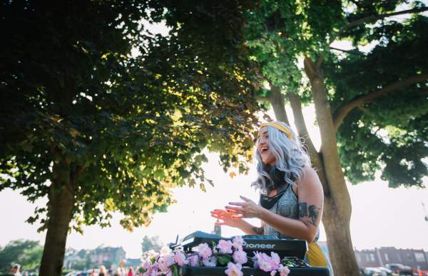 Young girl singing and clapping under trees with sun in background