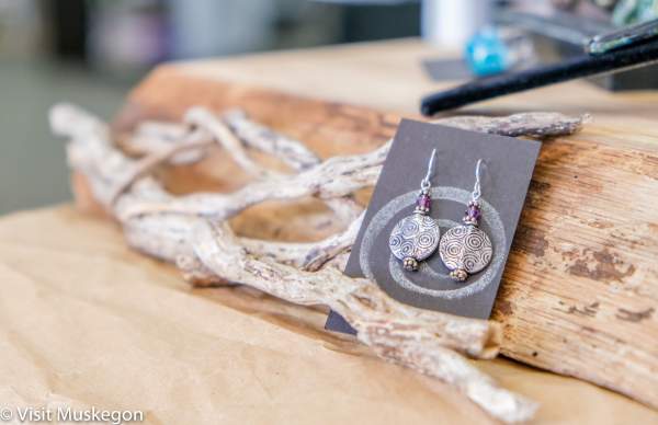 silver earrings on sales card rest against driftwood