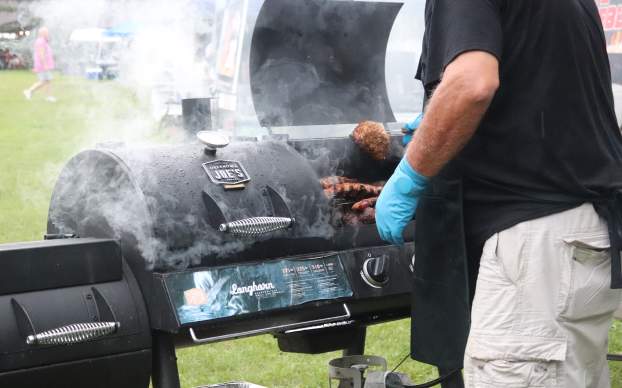 A black smoker with raindrops falling. There are ribs in the smoker.